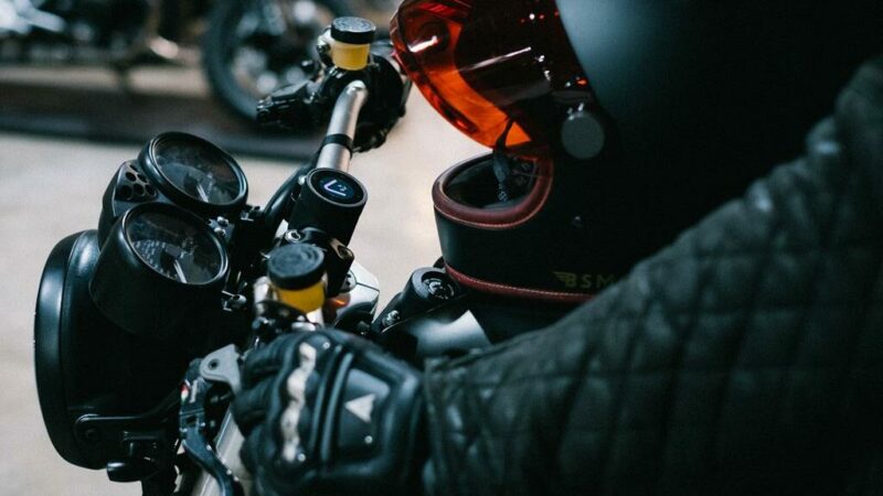 Foto de um motoqueiro utilizado jaqueta e luva preta